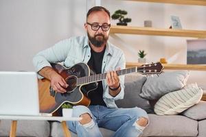 liedjes schrijven werkwijze. Mens in gewoontjes kleren en met akoestisch gitaar is binnenshuis foto