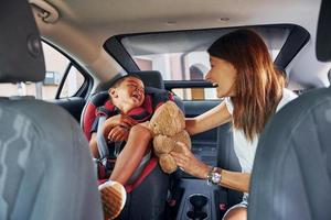 voorkant visie. vrouw met weinig jongen is in de modern auto- Bij dag foto