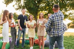 staand met cocktails. groep van jong mensen hebben een partij in de park Bij zomer dag foto