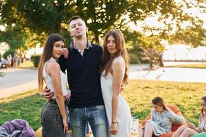 staand en hebben plezier. groep van jong mensen hebben een partij in de park Bij zomer dag foto