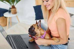 gebruik makend van laptop. vrouw met mopshond hond is Bij huis Bij dag foto