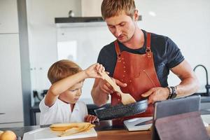 gebruik makend van tablet naar leren hoe naar koken. vader en zoon is binnenshuis Bij huis samen foto