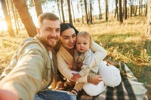 maken een selfie. gelukkig familie van vader, moeder en weinig dochter is in de Woud foto