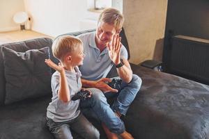 spelen video spel. vader en zoon is binnenshuis Bij huis samen foto