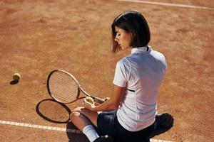 nemen een pauze. vrouw tennis speler is Aan de rechtbank Bij dag foto