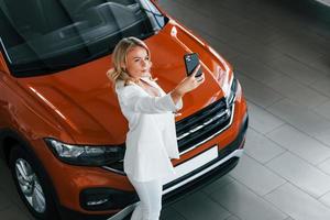 maken selfie. vrouw in formeel kleren is binnenshuis in de autosalon foto