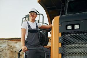 Aan de voertuig. arbeider in professioneel uniform is Aan de lenen pit Bij dag foto