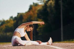 zittend Aan de grond. jong vrouw in sportief kleren is oefenen buitenshuis foto