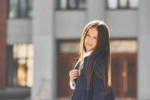 tegen gebouw. schoolmeisje is staand buiten foto