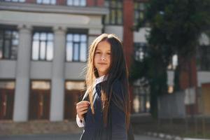 schoolmeisje is buiten in de buurt school- gebouw foto