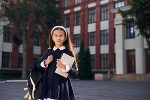 na lessen. schoolmeisje is buiten in de buurt school- gebouw foto