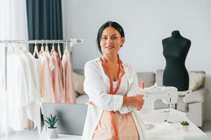 staand en poseren. naaister is in haar kantoor dat is met verschillend kleren foto