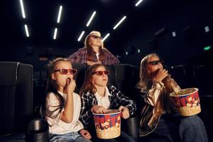 aan het eten popcorn. groep van kinderen zittend in bioscoop en aan het kijken film samen foto