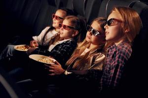 in 3d bril. groep van kinderen zittend in bioscoop en aan het kijken film samen foto