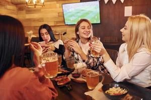 pratend met elk ander. groep van jong vrienden zittend samen in bar met bier foto