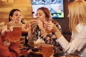 pratend met elk ander. groep van jong vrienden zittend samen in bar met bier foto