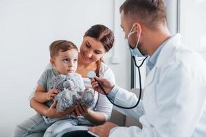 helpen de kind. twee artsen in wit jassen is in de kliniek werken samen foto