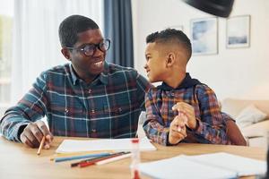 tekening lessen. Afrikaanse Amerikaans vader met zijn jong zoon Bij huis foto