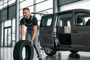 tijd naar verandering banden. Mens in uniform is werken in de autosalon Bij dag foto