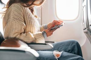 zittend met telefoon in handen. jong vrouw passagier in gewoontjes kleren is in de vlak foto