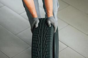 installeren nieuw band. Mens in uniform is werken in de autosalon Bij dag foto