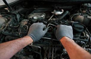 eerste persoon visie van man's handen dat reparaties auto. opvatting van auto- onderhoud foto