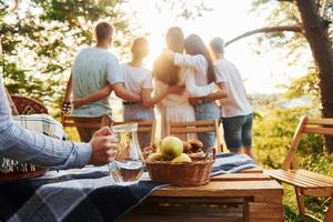 omarmen elk andere en op zoek Bij zonsondergang. groep van jong mensen hebben vakantie buitenshuis in de Woud. opvatting van weekend en vriendschap foto