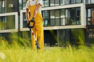 dichtbij omhoog visie. Mens besnoeiing de gras met gazon verhuizer buitenshuis in de werf foto