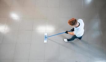 top visie van Mens in blauw overhemd en beschermend handschoenen dat toepassingen vacuüm schoonmaakster foto