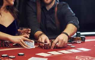 dichtbij omhoog visie van elegant jong mensen handen dat spelen poker in casino foto