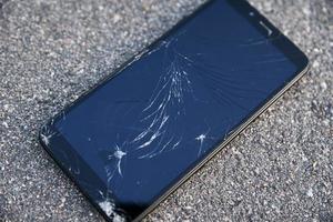 beschadigd smartphone met gebroken tintje scherm Aan asfalt foto