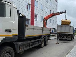 een groot, krachtig vuilnis vrachtauto lost vuilnis met een manipulator voor volgend recycling van middelen foto