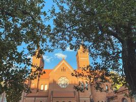 Katholiek kerk in de park. religieus plaats. tempel van geloof en religie achter groen bomen. gebrandschilderd glas venster Aan de kerk foto