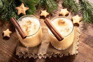 top visie naar twee bril van Kerstmis Advocaat met kaneel, Spar takken, koekjes sterren Aan houten tafel. foto