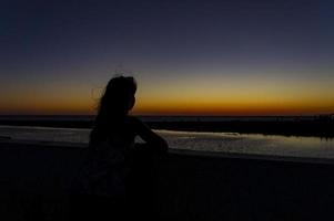 silhouet van een jong vrouw met fladderend haar- tegen de achtergrond van een helder zonsondergang foto