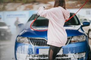 jong vrouw het wassen blauw auto Bij auto wassen foto