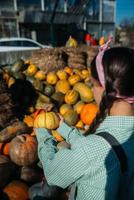 vrouw met een klein pompoen tussen de herfst oogst foto