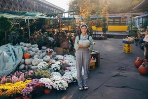 gelukkig boer vrouw in een denim jumpsuit houdt rijp pompoen foto