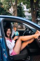 jong vrouw zittend in een auto en Holding een wereldbol foto