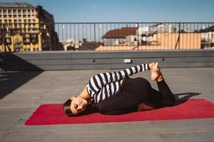 vrouw aan het doen yoga opdrachten Aan huis dak in vroeg ochtend- foto