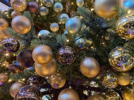 groen takken van een pluizig Kerstmis feestelijk nieuw jaar boom met speelgoed in ballen en helder gloeiend licht bollen en slingers, achtergrond foto