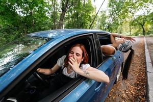 twee vriendinnetjes dwaas in de omgeving van en lachend samen in een auto foto