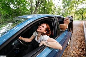 twee vriendinnetjes dwaas in de omgeving van en lachend samen in een auto foto