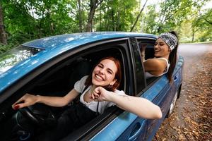 twee vriendinnetjes dwaas in de omgeving van en lachend samen in een auto foto