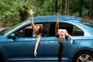 twee vriendinnetjes dwaas in de omgeving van en lachend samen in een auto foto