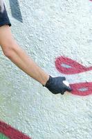 een hand- in zwart handschoenen verven graffiti Aan een beton muur. onwettig vandalisme concept. straat kunst foto