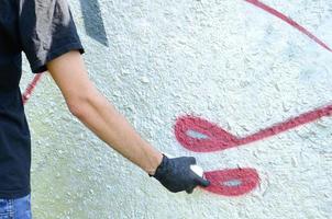een jong hooligan verven graffiti Aan een beton muur. onwettig vandalisme concept. straat kunst foto