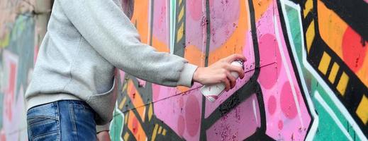 hand- van een jong vent in een grijs capuchon verven graffiti in roze en foto