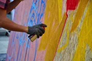 een hand- met een verstuiven kan dat trekt een nieuw graffiti Aan de muur. foto van de werkwijze van tekening een graffiti Aan een houten muur detailopname. de concept van straat kunst en onwettig vandalisme