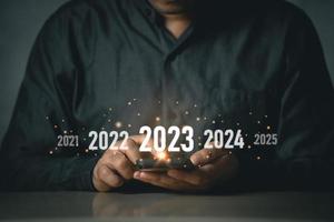 nieuw jaar 2023 concept. begin gelukkig nieuw jaar 2023. zakenman freelance investeerders gebruik makend van mobiel telefoon tintje scherm virtueel 2023 jaar diagram, bedrijf planning, strategie, bedrijf trends, investering. foto